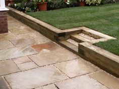 a garden area with grass and plants in the back ground, surrounded by brick walkways