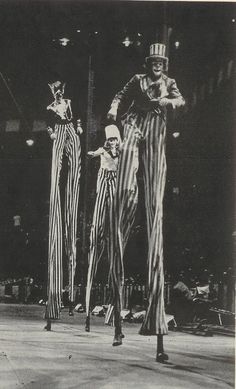 three circus clowns in striped pants and top hats