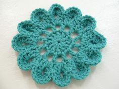 a green crocheted doily on a white surface with the center being made from yarn