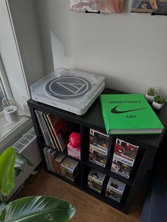 a record player sitting on top of a book shelf next to a potted plant