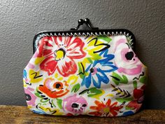 a colorful flowered purse sitting on top of a wooden table next to a gray wall