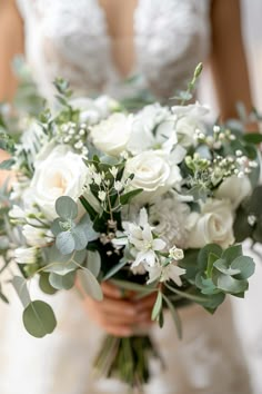 a bridal holding a bouquet of white flowers and greenery