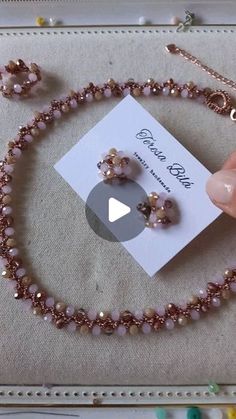 a pink necklace and earring set on display in a jewelry box next to a card