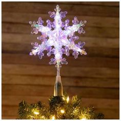 a lighted snowflake on top of a christmas tree