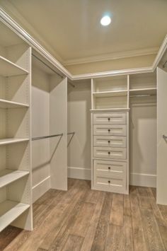 an empty walk in closet with lots of shelves and drawers on the wall, along with wooden flooring