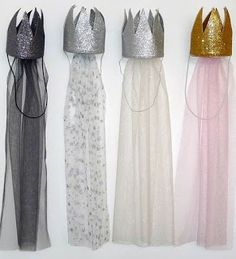 four dresses with crowns on them are lined up in a row against a white wall