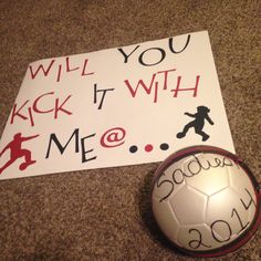 a soccer ball sitting next to a sign that says, will you kick it with me?