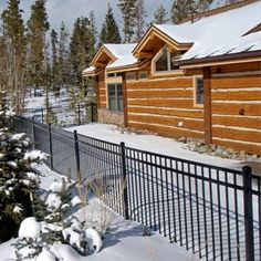 a fence is covered in snow next to a log cabin