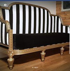 a black and white striped couch sitting on top of a hard wood floor next to a wall