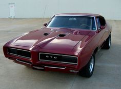 a red muscle car parked in a parking lot