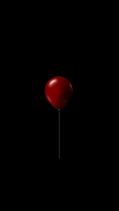 a red balloon is floating in the dark