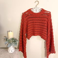 a red sweater hanging on a wall next to a candle