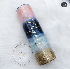 a blue and pink tube with gold glitter on it sitting on top of a white fur