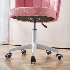 a pink office chair with wheels in front of a window