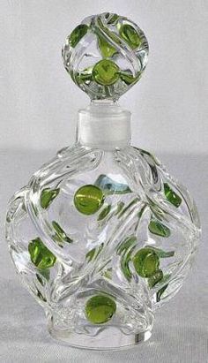 a clear glass bottle with green leaves on the top and bottom, sitting on a white surface