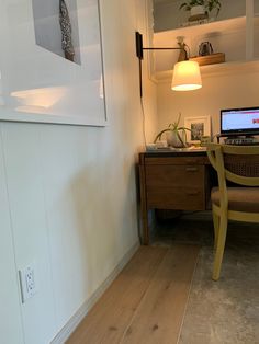 a laptop computer sitting on top of a wooden desk next to a lamp and chair