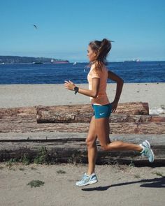 a woman running on the beach near water