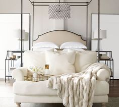 a bed with white sheets and pillows in a room