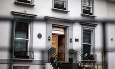 a building with stairs leading up to the front door and two windows on each side