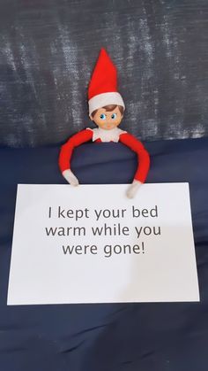 an elf holding a sign that says i kept your bed warm while you were one