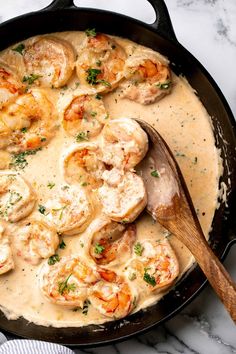 a skillet filled with shrimp and grits on top of a marble countertop