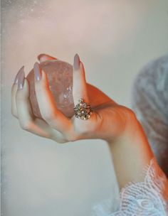 a woman is holding a rock in her right hand and wearing a ring on it