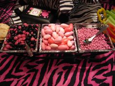 three trays filled with different types of candies on a zebra print table cloth