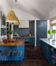 a kitchen with blue cabinets and stools in front of the counter top, along with an area rug on the floor