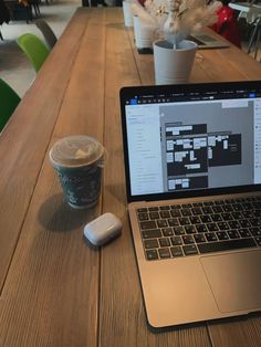 an open laptop computer sitting on top of a wooden table next to a cup of coffee