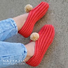 a woman wearing red crocheted slippers with pom - poms on the toes