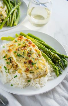 a white plate topped with chicken and rice next to asparagus