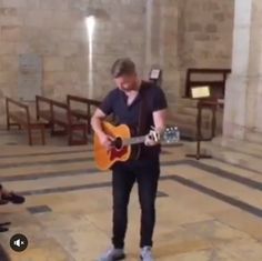 a man is playing an acoustic guitar in a church