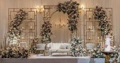 a room filled with lots of tables and chairs covered in white flowers, greenery and chandeliers