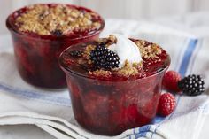 two desserts with berries and yogurt in them on a towel next to some raspberries