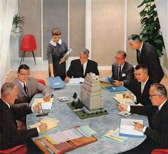 a group of men sitting around a table with books and papers in front of them