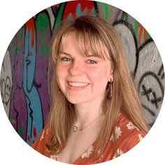 a woman smiling in front of some graffiti