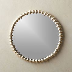 a round mirror mounted to the wall with spikes on it's sides, reflecting light