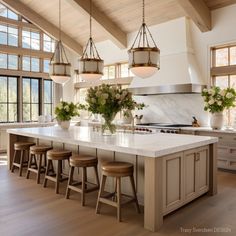 a large kitchen island with stools in front of it and lots of windows on the side