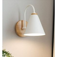 a white lamp mounted on the wall next to a potted plant