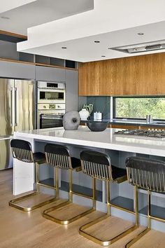 modern kitchen with stainless steel appliances and counter tops, along with bar stools that match the hardwood flooring