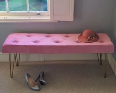 a pink bench with two legs and a hat on top, next to a pair of shoes