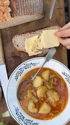 a bowl of soup with bread and butter on the side, ready to be eaten