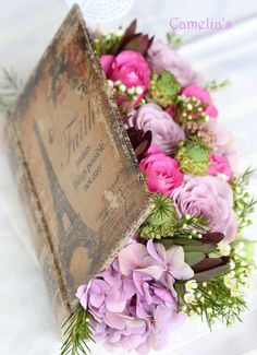 a bouquet of flowers sitting on top of a table next to an old box with the eiffel tower in it