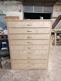 a wooden dresser sitting on top of a floor next to a pile of wood planks