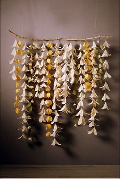 an arrangement of white and yellow flowers hanging from a string on a wall in a room