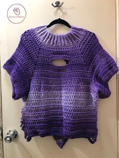 a purple crocheted sweater hanging on a door