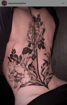 a woman's lower back with flowers on her stomach and the bottom half covered in black ink