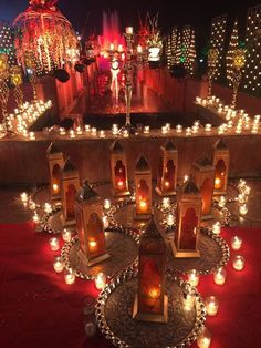 many lit candles are placed on the ground in front of a stage with lights and decorations