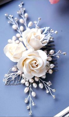 a white rose and pearl hair comb on a blue surface