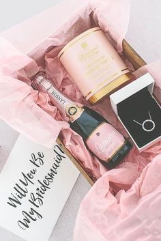 an open pink box containing two bottles of wine, a ring and a note that says wildflowers